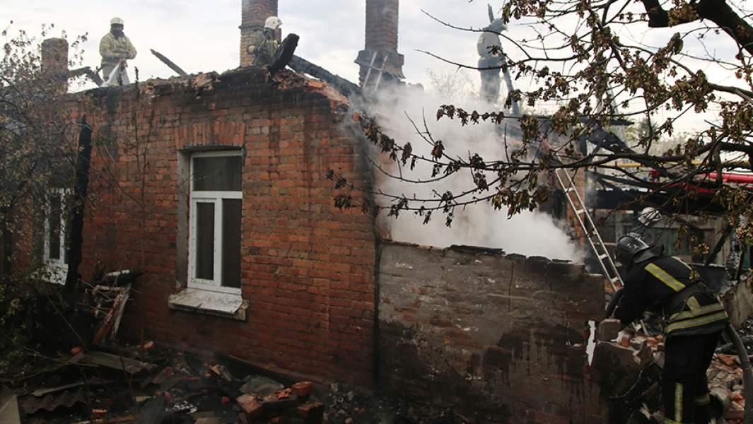 Сотрудники пожарной службы на месте пожара в жилом доме, разрушенном в результате обстрела