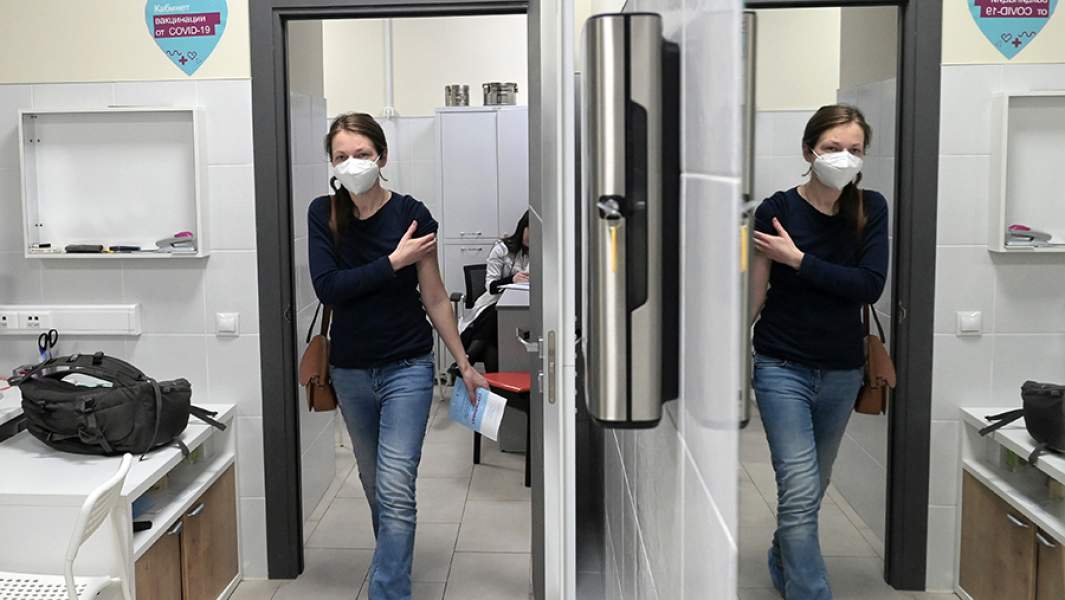 Женщина выходит из кабинета после вакцинации от COVID-19