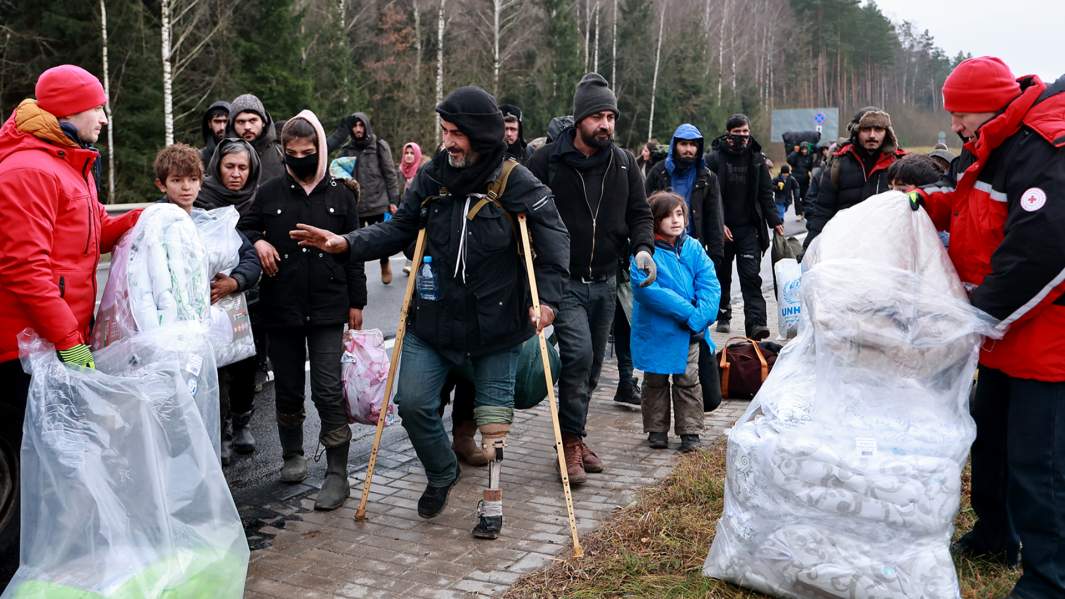 Беженцы с Ближнего Востока получают гуманитарную помощь по дороге в центр временного содержания мигрантов, оборудованный в логистическом центре в пункте пропуска «Брузги» на белорусско-польской границе