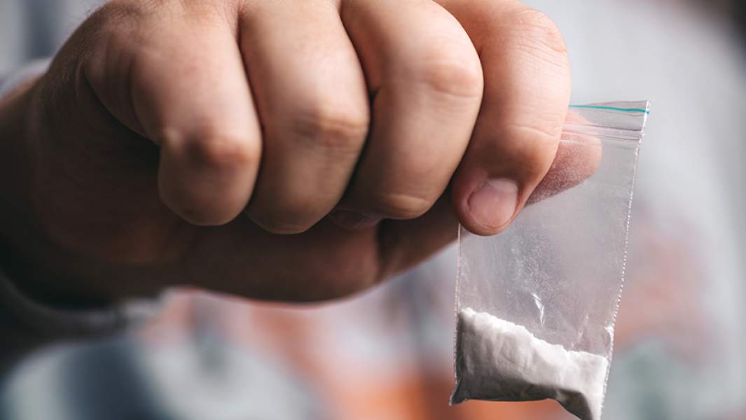 Подросток держит в руке пакетик с наркотическим веществом 