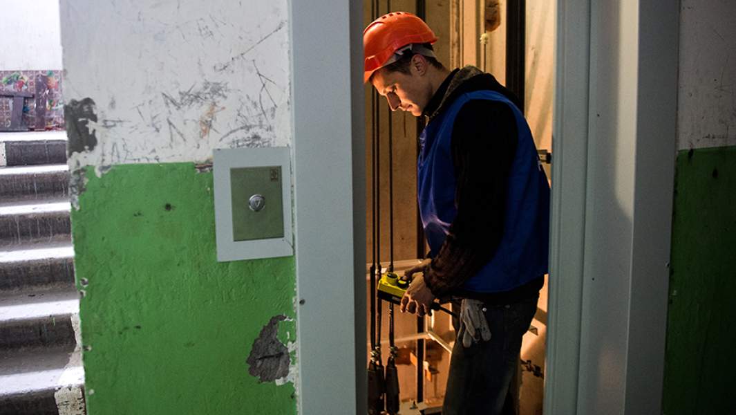 Рабочий регионального фонда капитального ремонта многоквартирных домов ремонтирует лифт в жилом доме