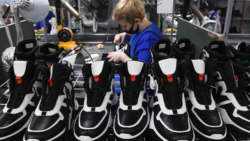 Сотрудник на этапе производства обуви на предприятии 