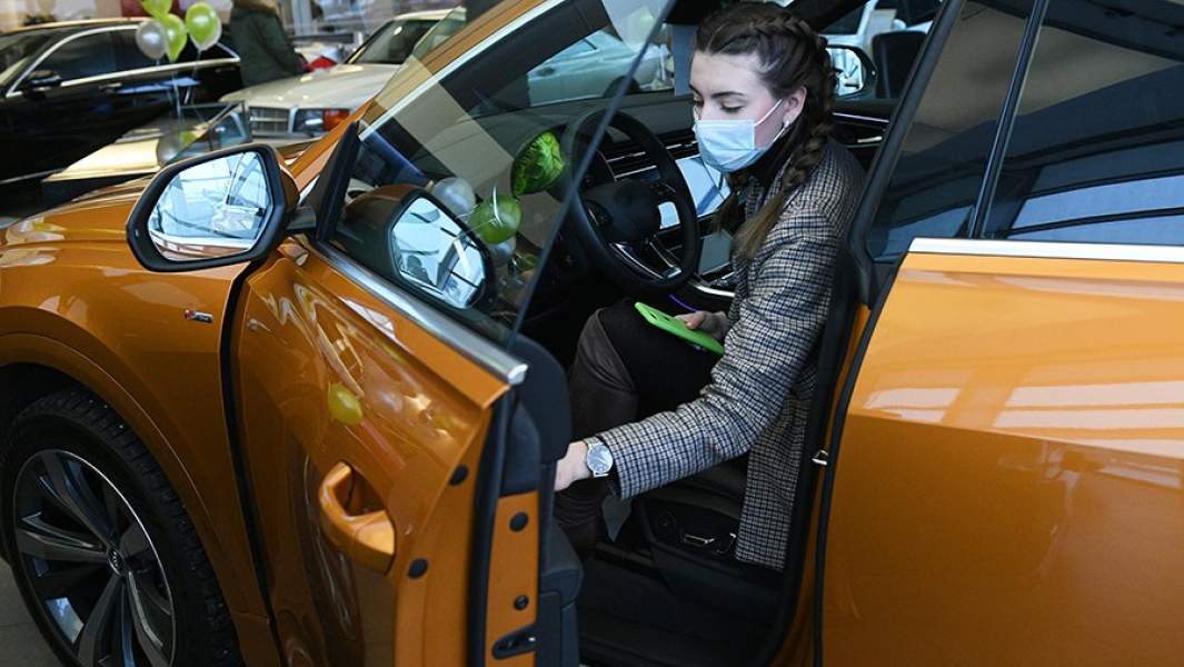 Менеджер демонстрирует покупателям автомобиль в автосалоне