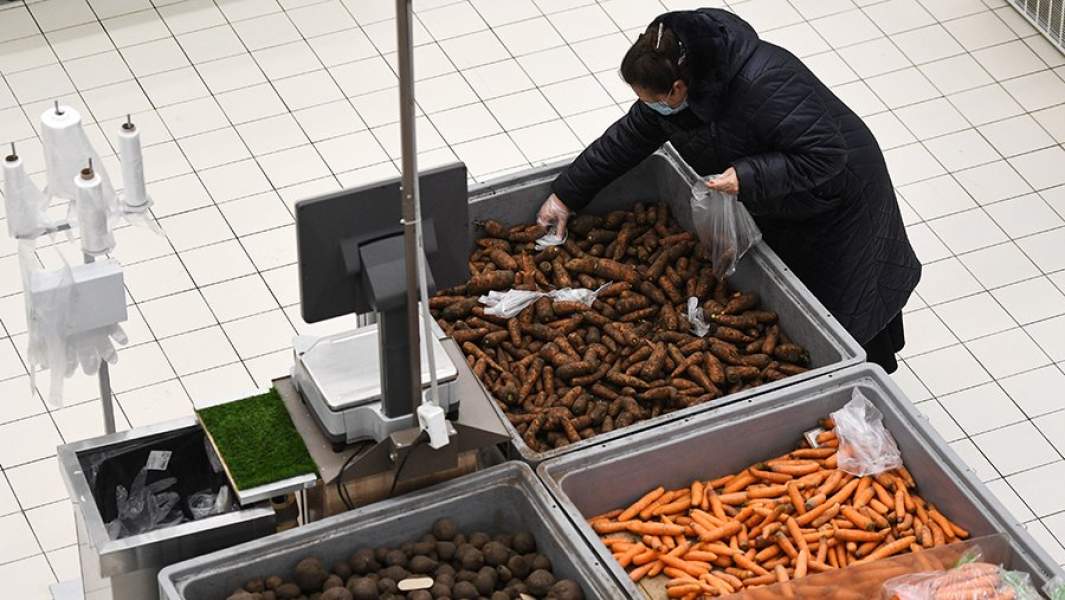 Покупательница набирает морковь в гипермаркете