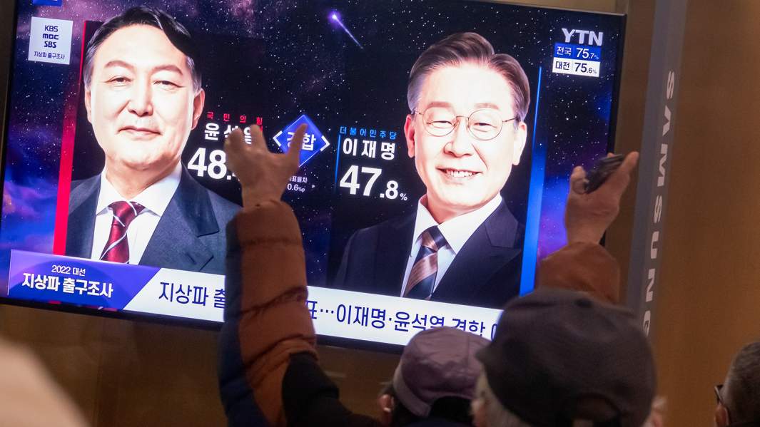 Люди смотрят прямую трансляцию объявления результатов экзитполов президентских выборов на вокзале в Сеуле, Южная Корея. 