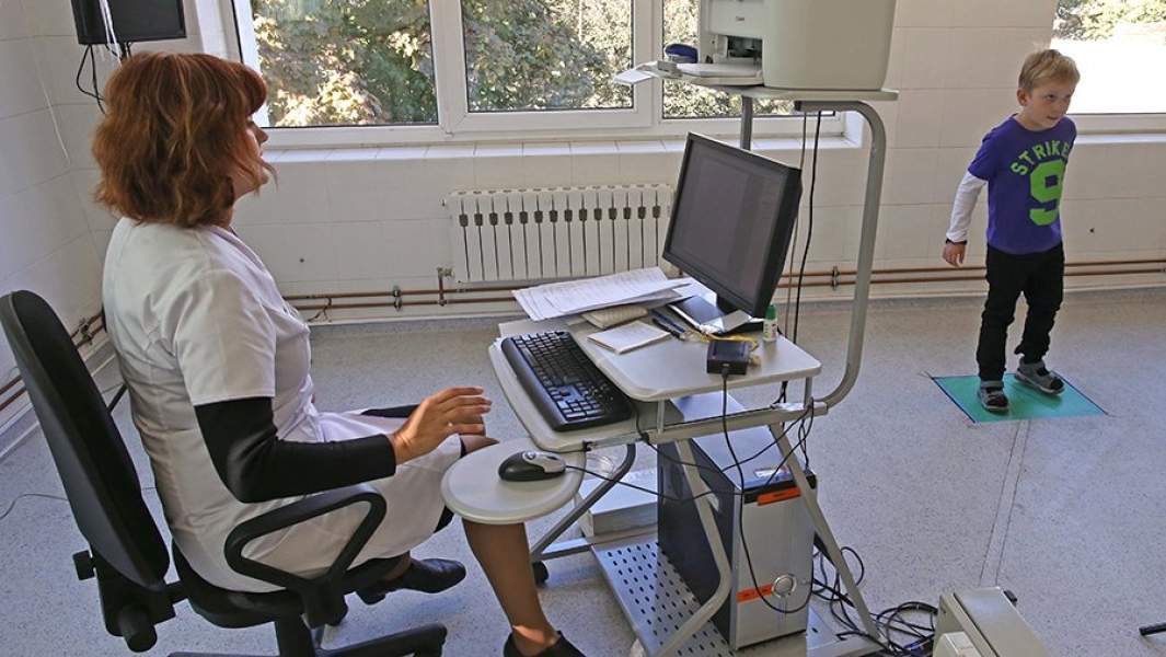Сотрудница детского ортопедического санатория проводит процедуру компьютерной коррекции баланса