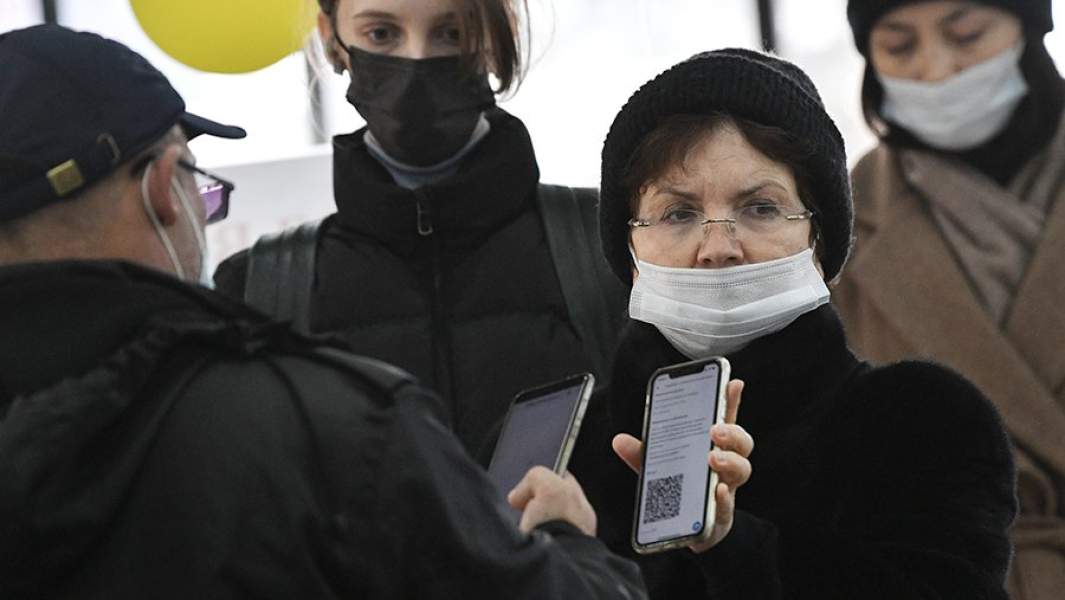 Пожилая женщина в защитной маске показывает QR-код