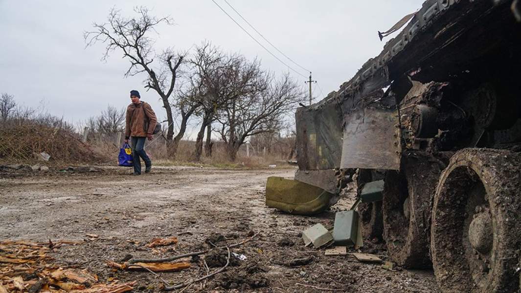 Житель села Гнутово идет мимо подбитого танка украинской армии под Мариуполем