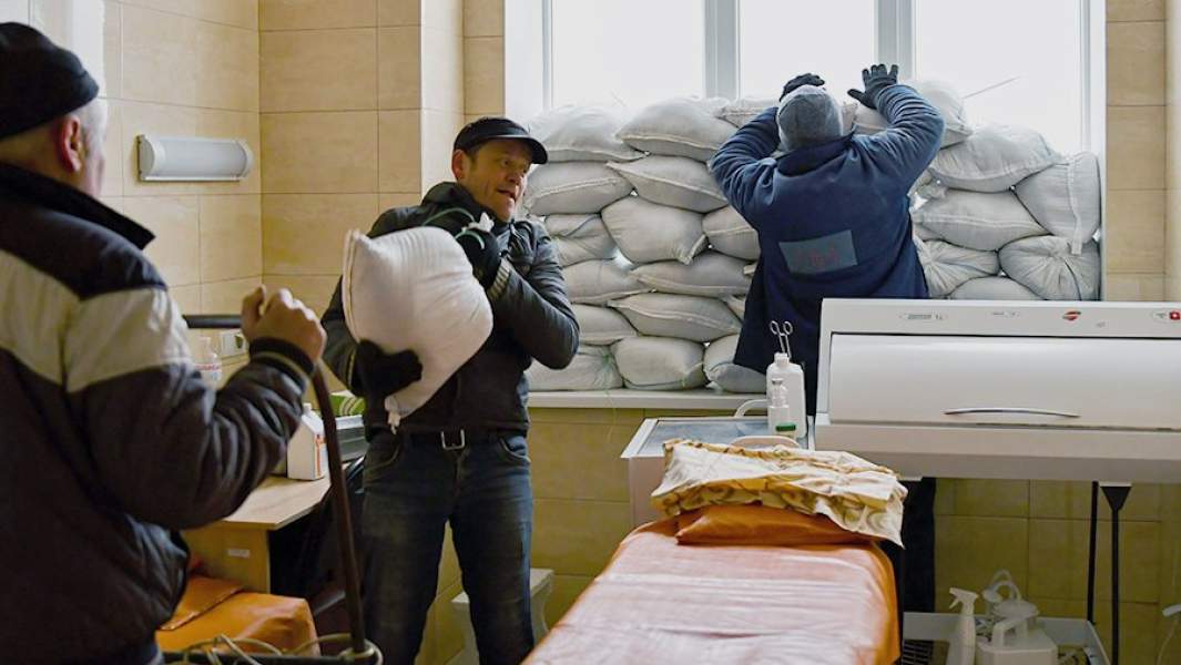 Работники закрывают окна мешками с песком в больнице