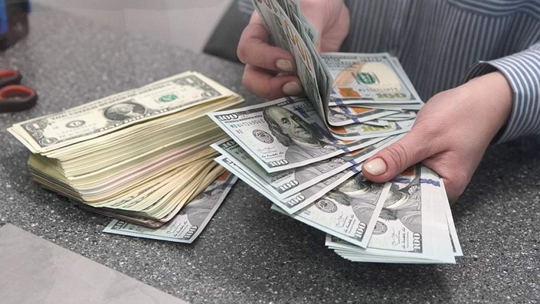 Женщина пересчитывает валюту в банке