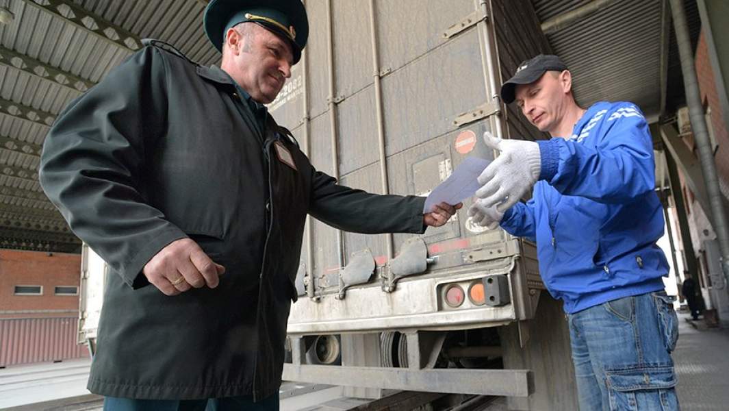 Сотрудник таможни и водитель после осмотра грузового автомобиля