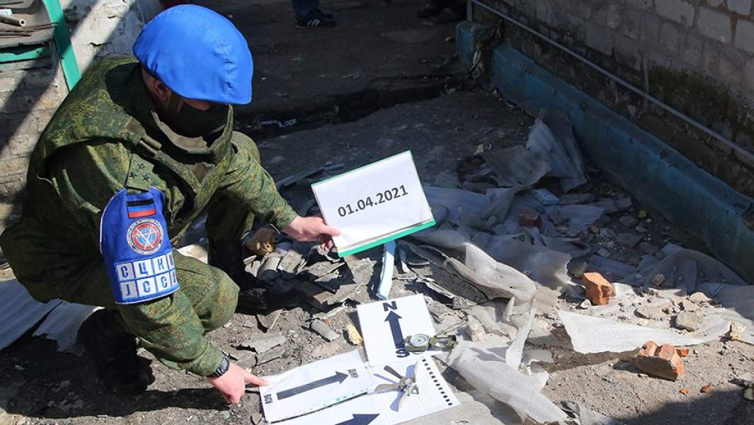 Представитель СЦКК ДНР фиксирует фрагменты снаряда, найденные на месте обстрела частного жилого дома в поселке Александровка Донецкой области