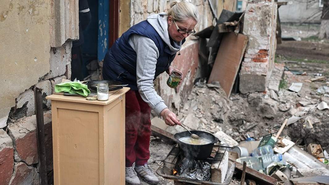 Женщина готовит еду во дворе жилого дома в Левобережном районе