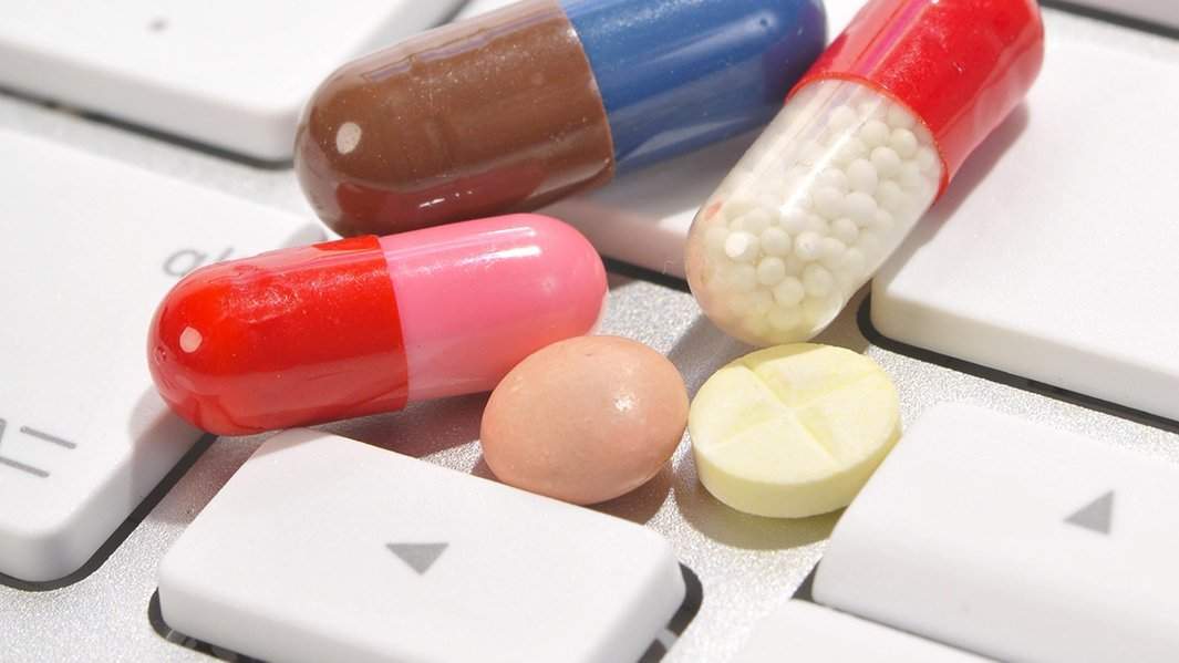 различные медикаменты лежат на клавиатуре ПК