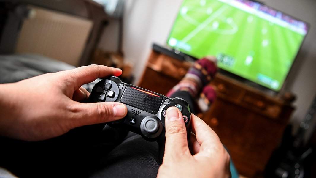 Человек играет в fifa на приставке