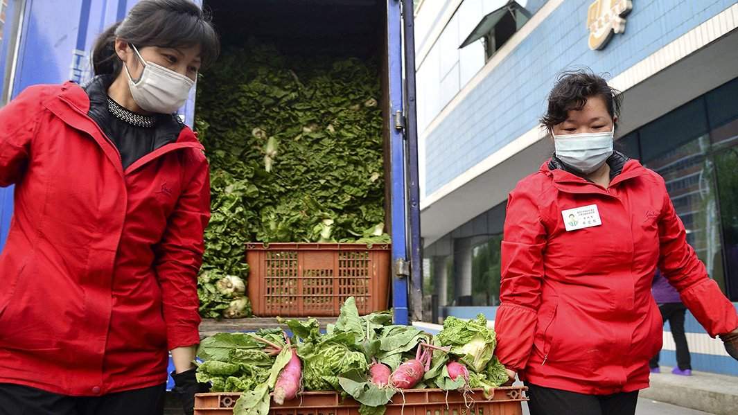 Рабочие в защитных масках несут овощи на фоне растущих опасений по поводу распространения COVID-19 в Пхеньяне