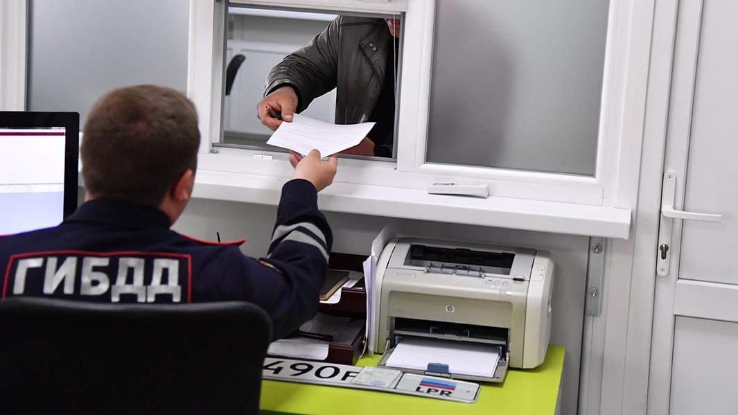 Сотрудник (МРЭО) УГИБДД МВД принимает документы от посетителя