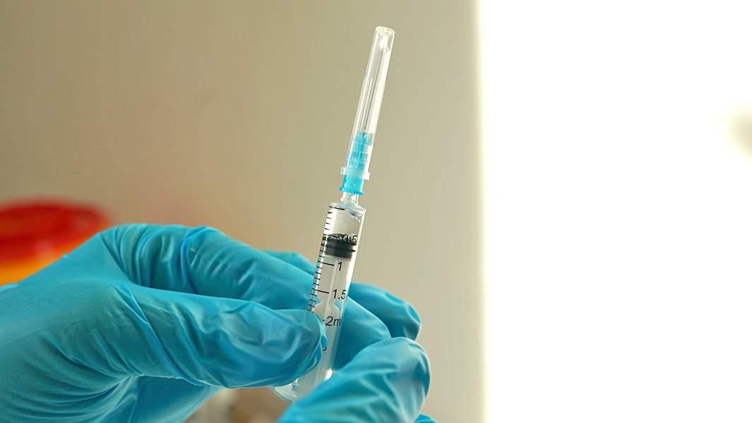 доктор выпускает воздух из шприца