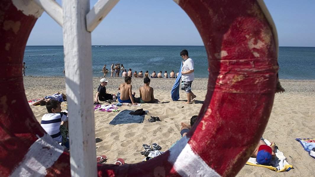 Отдыхающие на пляже Черного моря у детского оздоровительного лагеря