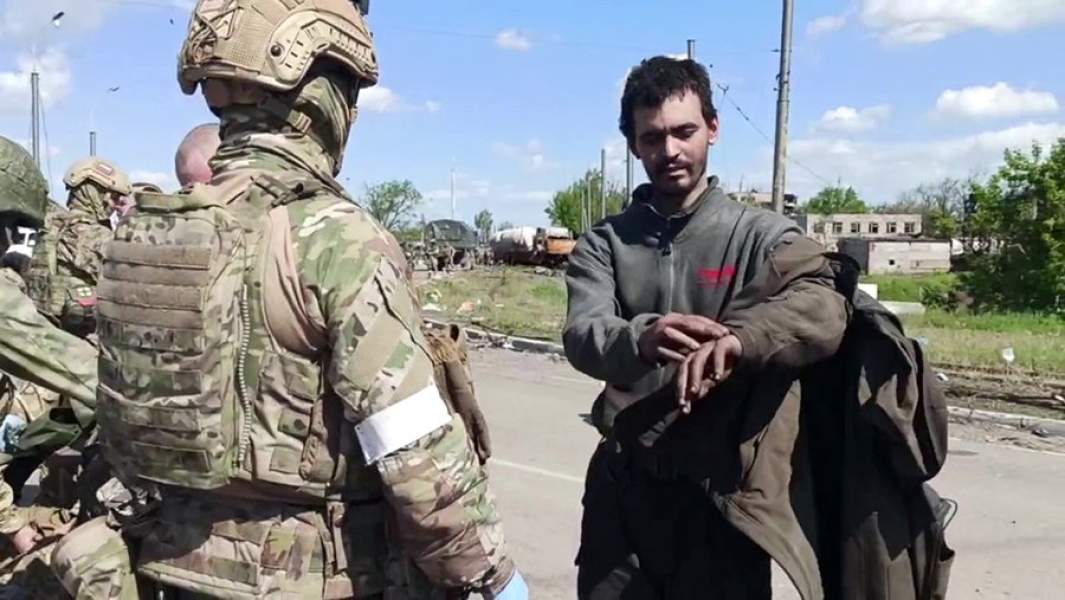 Российские военнослужащие досматривают сдавшихся в плен украинских военнослужащих