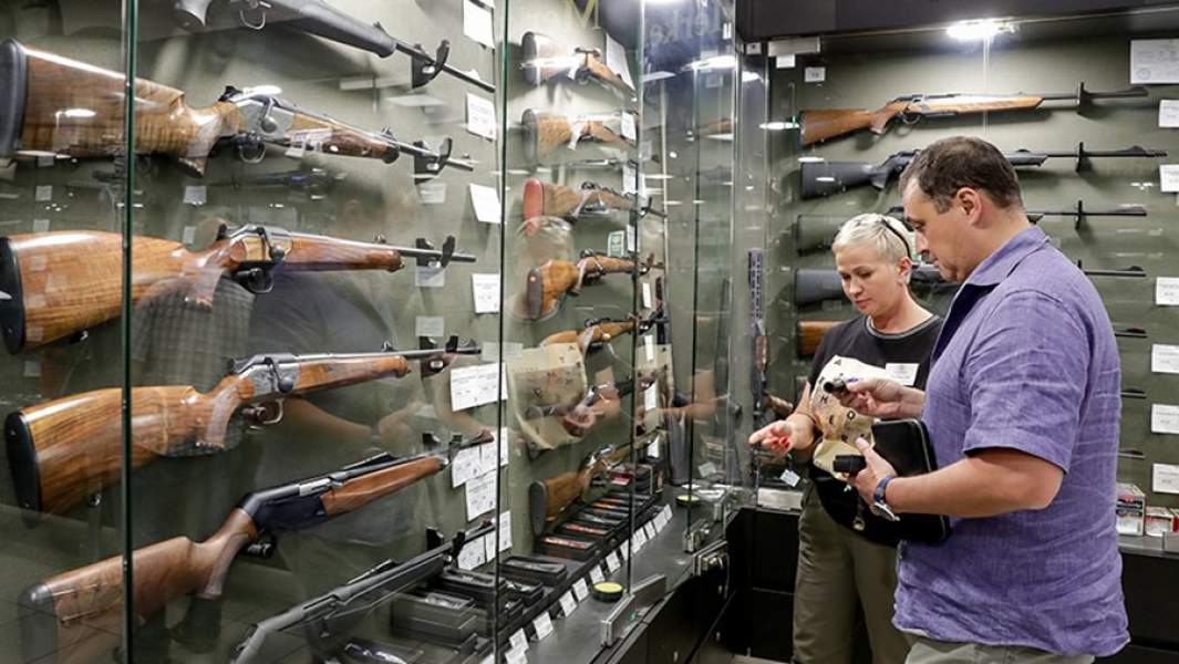 Продавец демонстрирует товары покупателю в оружейном магазине