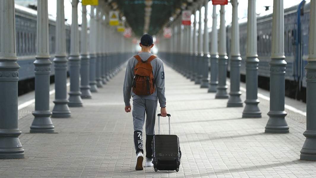 человек с чемоданом и рюкзаком идет по перрону