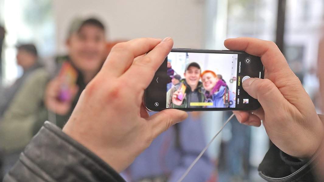 человек снимает на камеру, встроенную в смартфон, людей