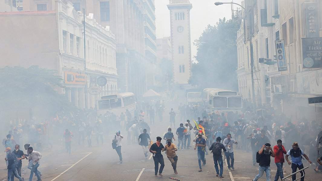 Демонстранты бегут от слезоточивого газа, примененного полицией во время акции протеста с требованием отставки президента Готабая Раджапакса, 9 июля 2022 года