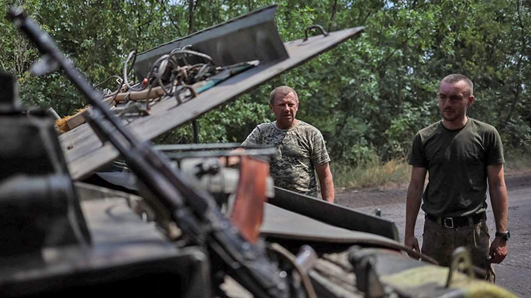 украинские военнослужащие стоят возле разбитой техники