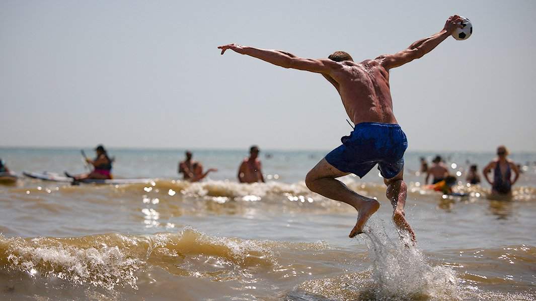 Любители пляжного отдыха охлаждаются в воде, чтобы спастись от жары в Бродстерсе в Великобритании