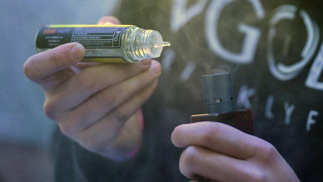 Мужчина заправляет вейп