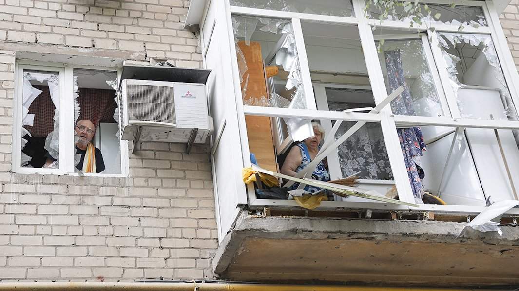 Местные жители в окнах своей квартиры в жилом доме в Киевском районе Донецка, частично разрушенном в результате обстрела со стороны ВСУ