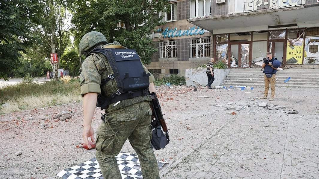 Сотрудник Следственного комитета ДНР изучает место взрыва снаряда после обстрела ВСУ жилых районов Донецка