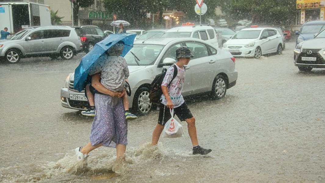 Люди на одной из подтопленных в результате ливня улиц в сочинском микрорайоне Ареда