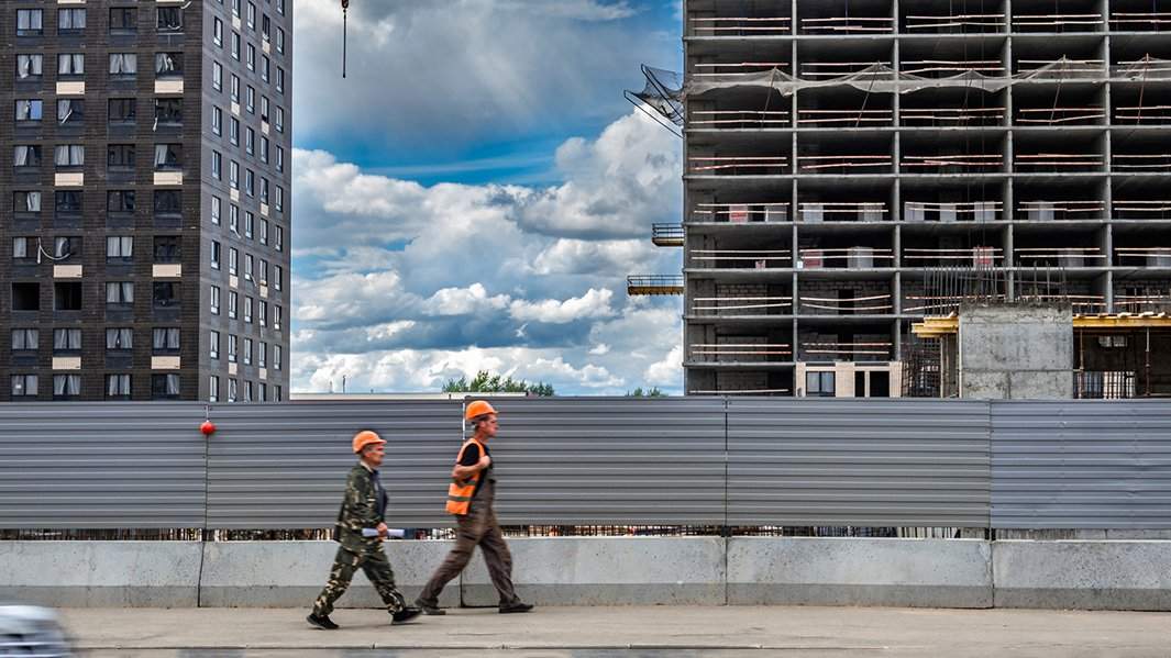 Рабочие идут мимо стройки
