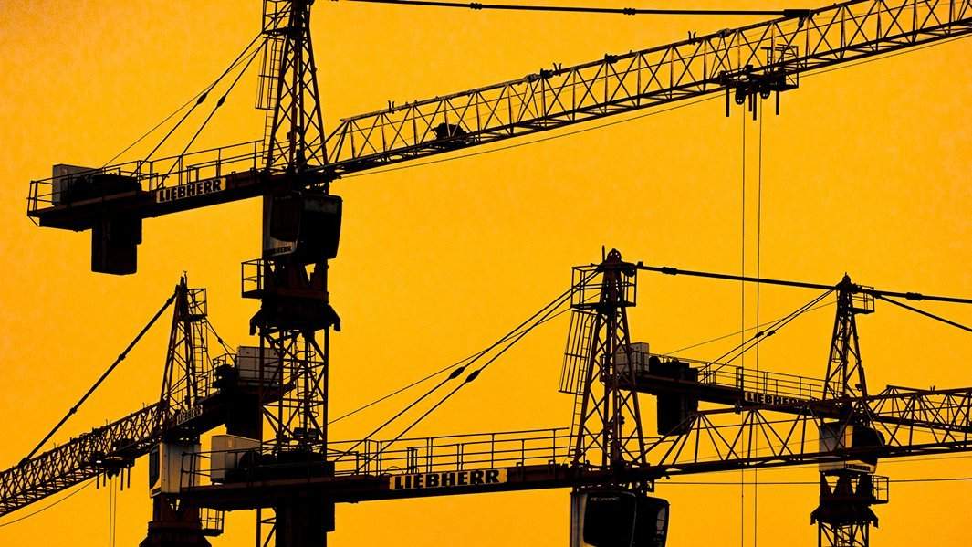 Строительные краны на фоне закатного неба