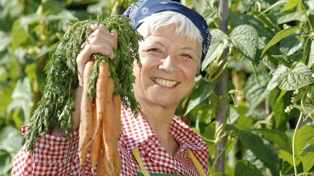 Счастливая пожилая женщина с морковками
