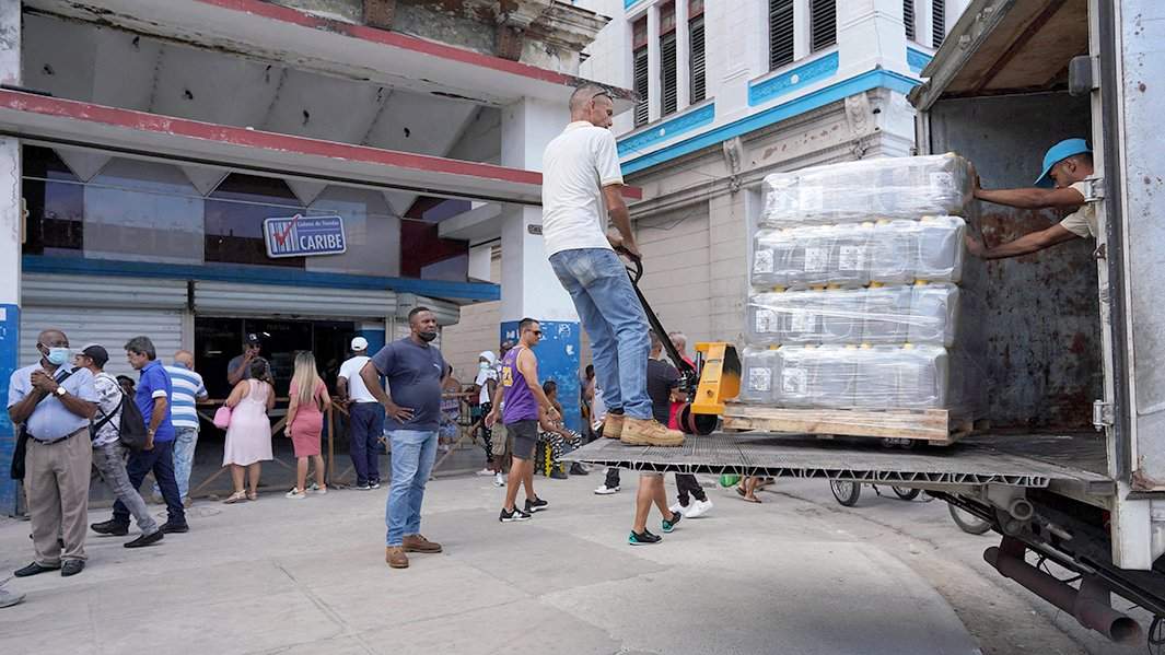 Рабочие выгружают растительное масло из грузовика перед магазином в центре Гаваны, Куба, 20 и