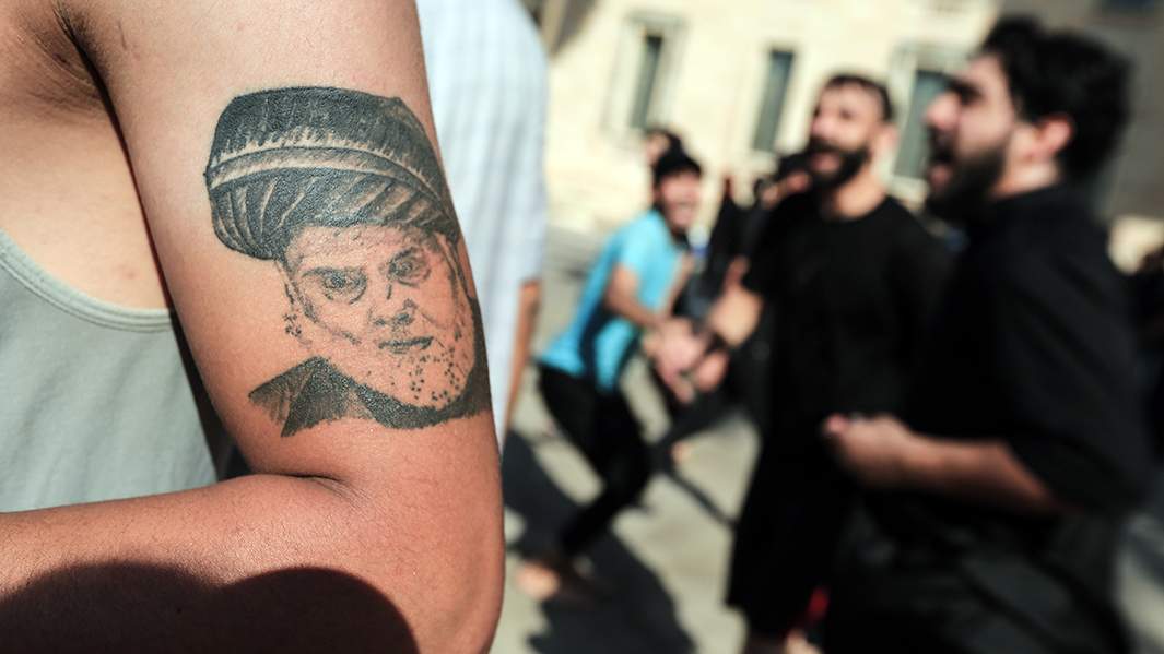 иракец с вытатуированным на руке портретом иракского шиитского священнослужителя Муктады ас-Садра во время акции протеста на территории Дворца правительства