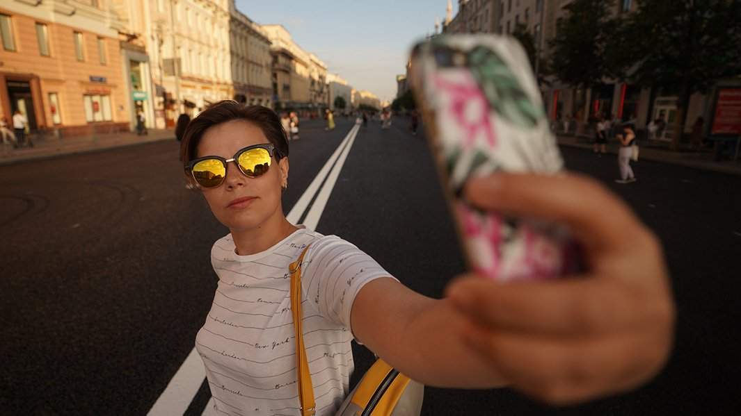 Девушка делает селфи в вечернем городе