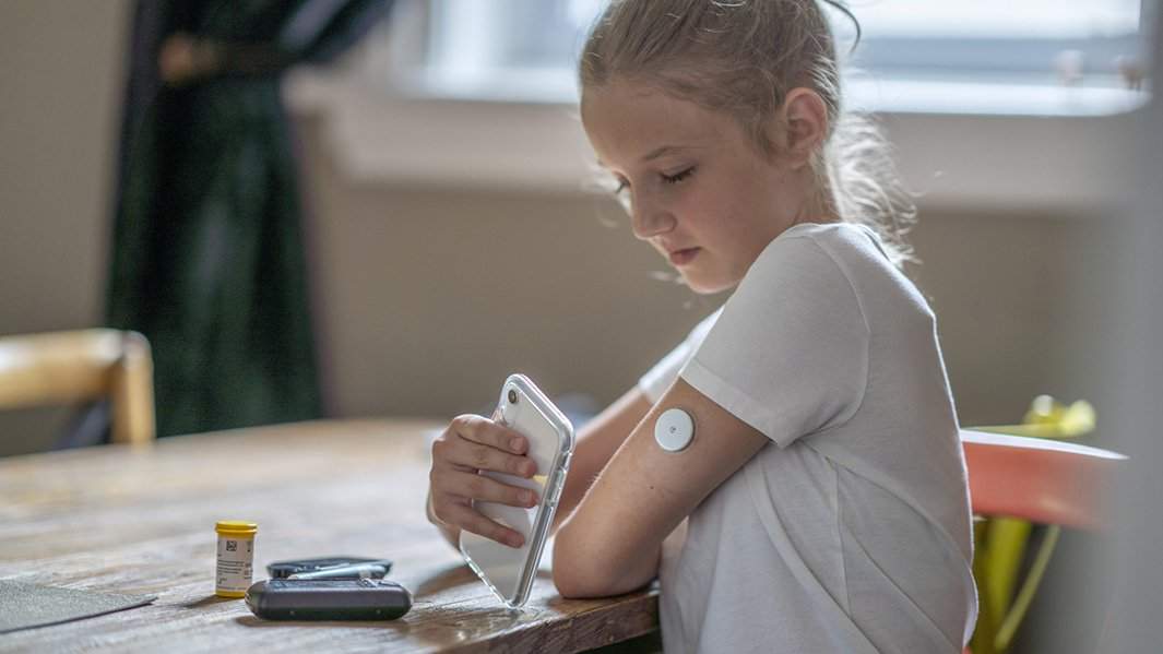 Девочка измеряет уровень глюкозы с помощью системы непрерывного мониторинга