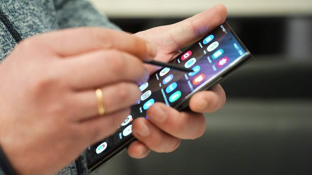 Человек держит в руках смартфон со стилусом