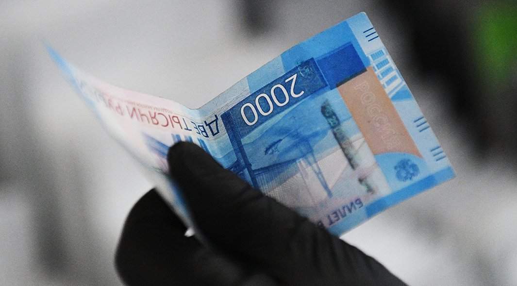 человек держит в руках российскую банкноту