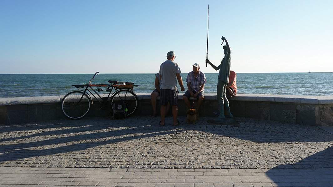 На набережной - рыбаки рядом с бронзовой фигурой мальчика-рыбака