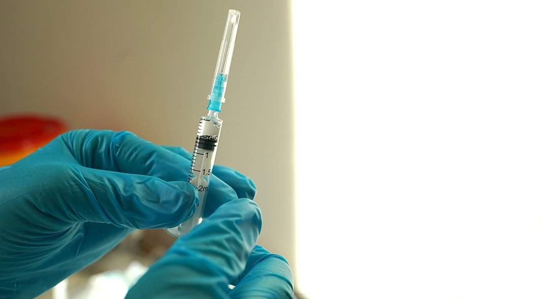 врач держит шприц для вакцинации