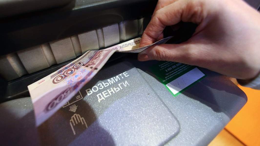 Женщина получает наличные деньги из банкомата