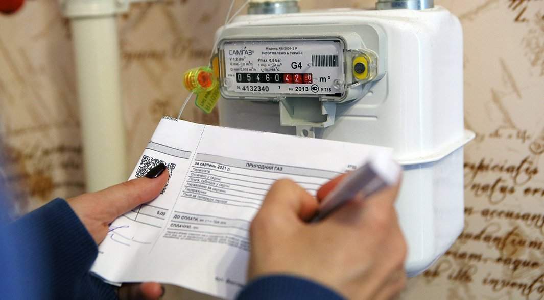 Девушка записывает показания счетчика учета газа у себя дома