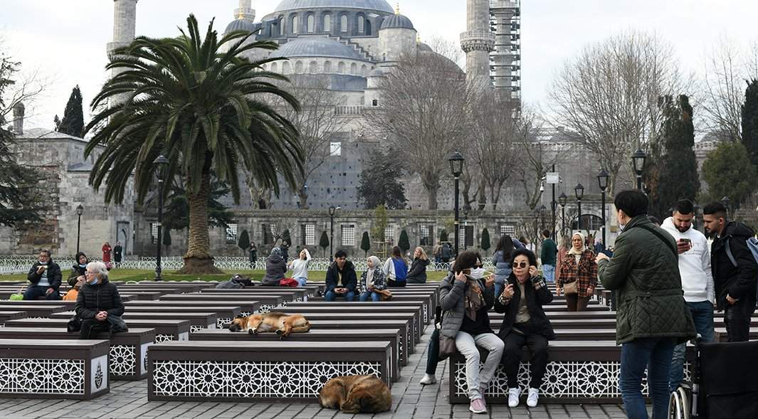 Люди отдыхают на скамейках в парке СултанАхмед