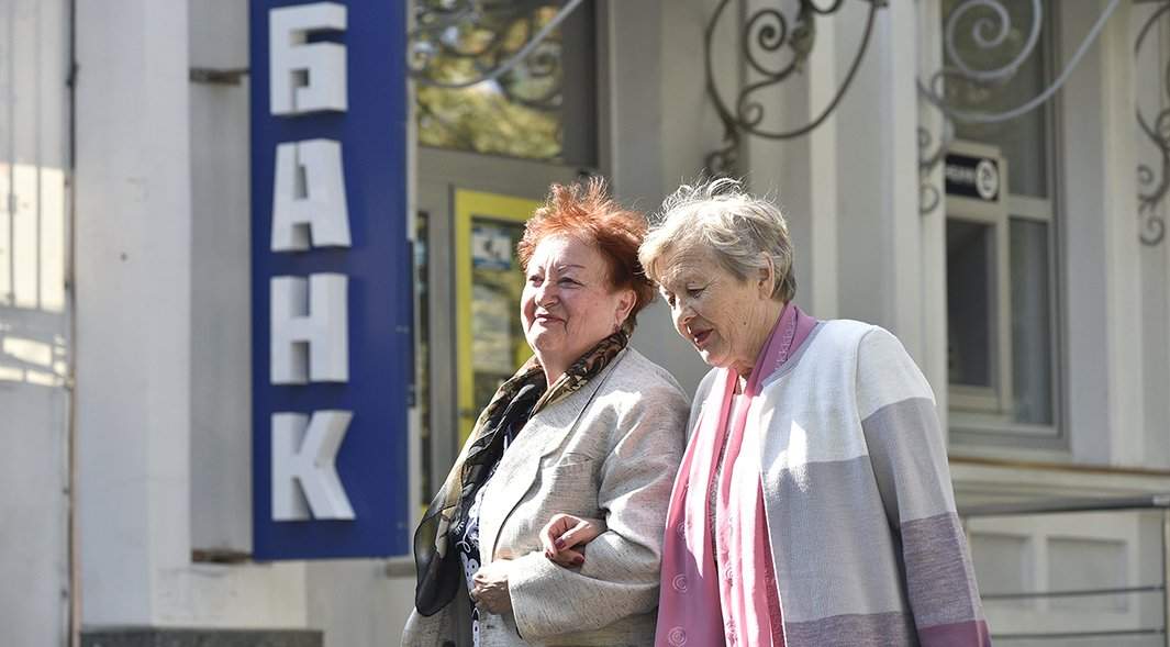 женщины проходят мимо отделения банка