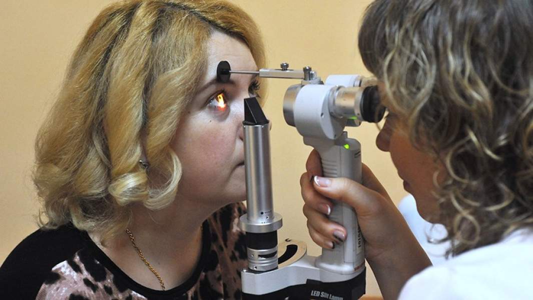 Врач-офтальмолог проводит осмотр пациента на щелевой лампе
